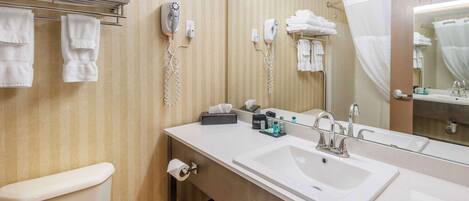 A bathroom with a large mirror, a sink, a toilet, and towel racks.