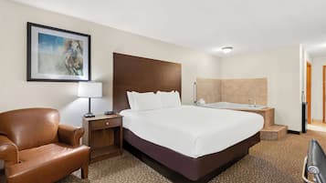 Habitació d'hotel amb un llit gran, una butaca de cuir marró, un escriptori amb una làmpada, un quadre a la paret i una banyera.