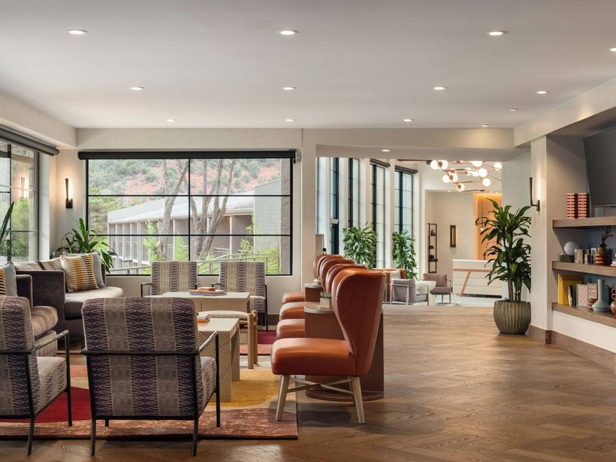 A spacious living area with a large window, multiple seating arrangements, and a central light fixture.