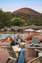 Un área junto a la piscina con sillones de descanso, una fogata y una piscina.