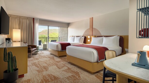 A hotel room with two beds, a desk, a dining table, a TV, and a cactus plant. - Outbound Sedona (Sedona)