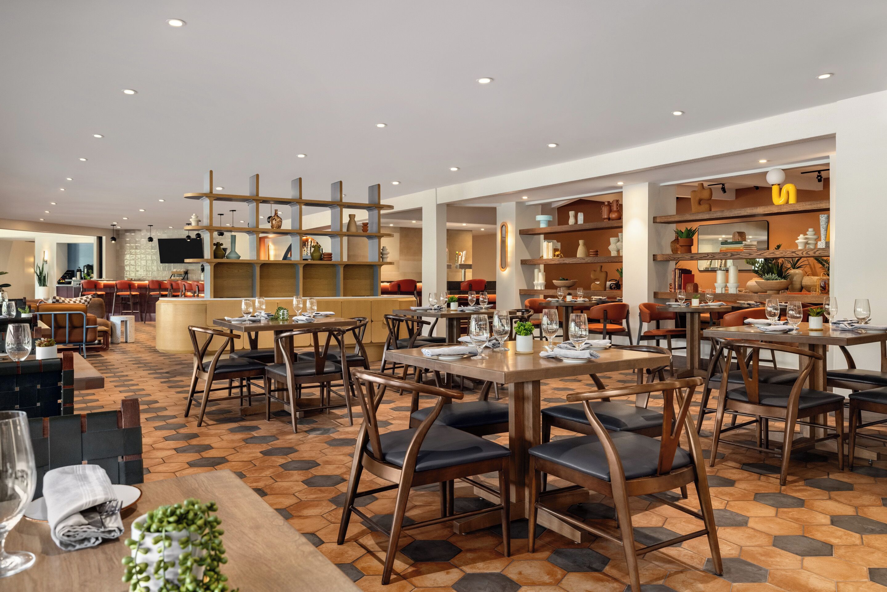 Ein Restaurant mit mehreren Essbereichen, darunter eine Bar sowie Sitzgelegenheiten mit Tischen und Stühlen.