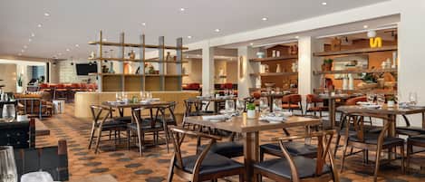A restaurant with multiple dining areas, including a bar and seating with tables and chairs.