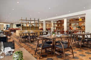 A restaurant with multiple dining areas, including a bar and seating with tables and chairs.