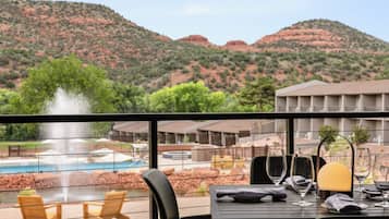 Una mesa de comedor con vista a una piscina y montañas.