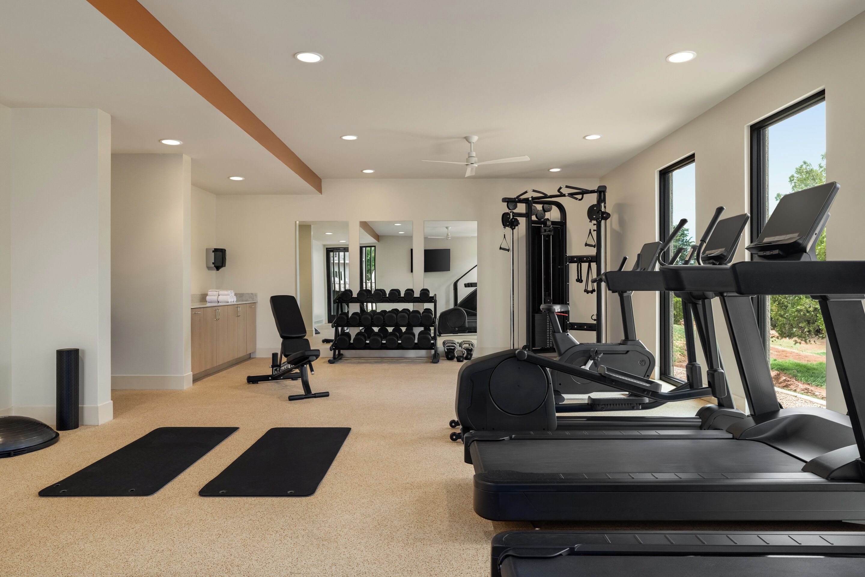 Un gimnasio con cintas de correr, una banca de pesas y un espejo.