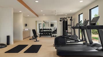 Un gimnasio con cintas de correr, una banca de pesas y un espejo.