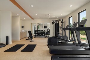 Un gimnasio con cintas de correr, una banca de pesas y un espejo.