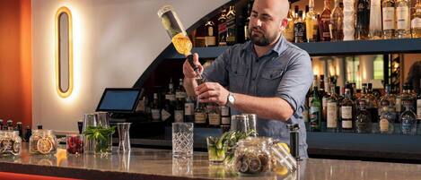A bartender at a bar with a variety of liquor bottles in the background.
