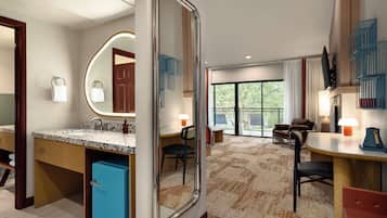 A hotel room with a bathroom, a dining area, and a living space.
