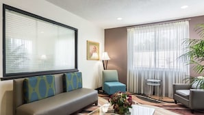 A hotel lobby with a sofa, chairs, a coffee table, and a large window with blinds. - Quality Inn Warsaw near Rappahannock River (Warsaw)