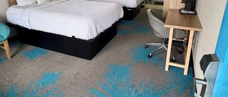 Una habitación de hotel con una cama grande, un escritorio, una silla y un baño.