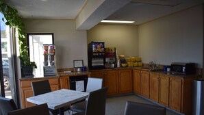 A kitchen with wooden cabinets, a marble countertop, and a dining area with chairs. - Days Inn by Wyndham Reidsville (Reidsville)