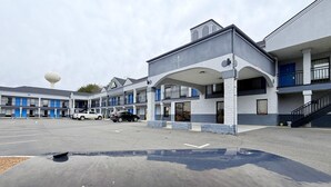 A motel with a central building and two wings, a parking lot, and a water tower in the background. - Days Inn by Wyndham Reidsville (Reidsville)