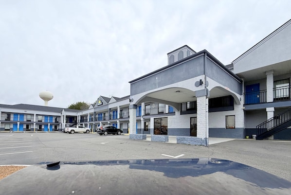 A motel with a central building and two wings, a parking lot, and a water tower in the background. - Days Inn by Wyndham Reidsville (Reidsville)