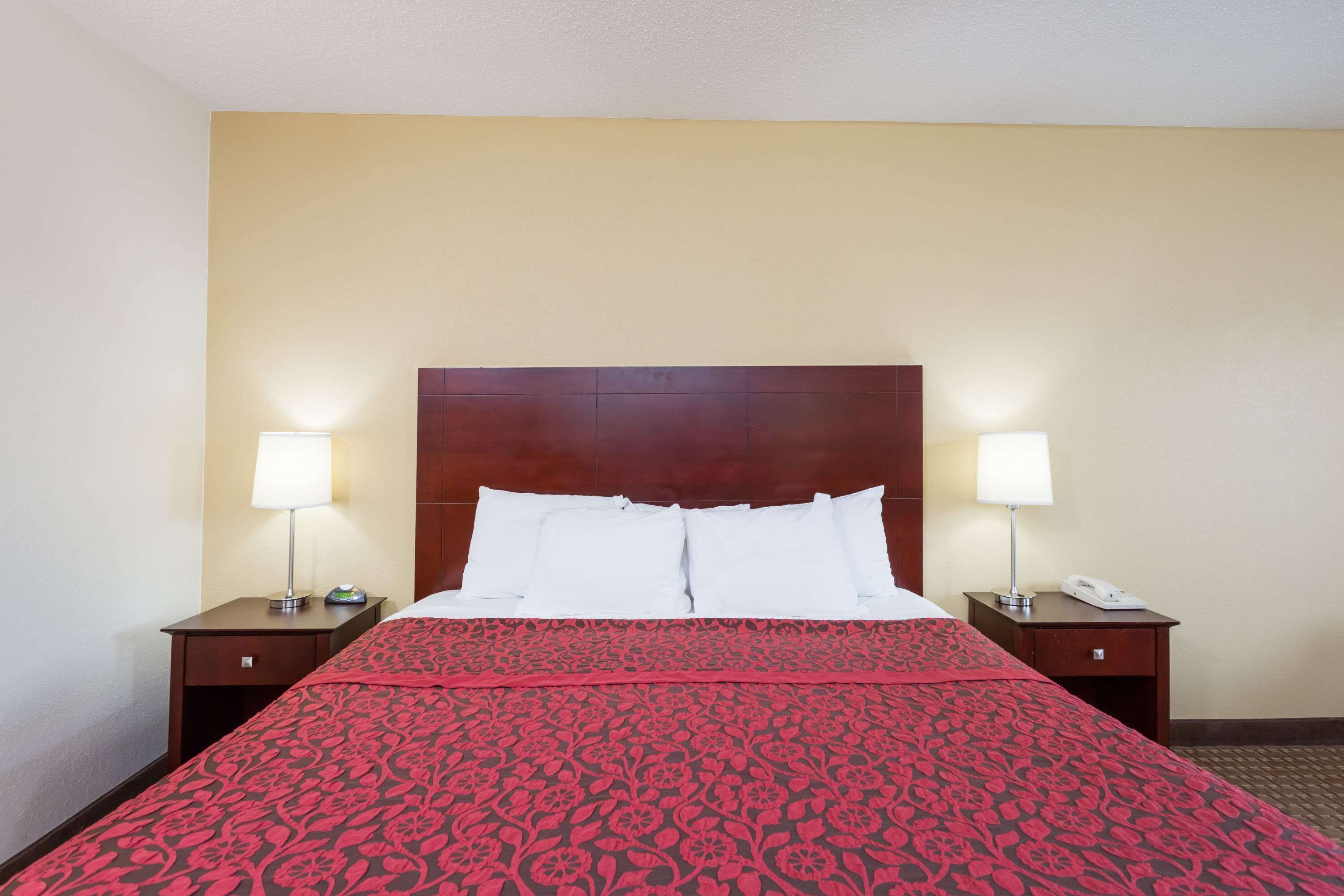 A hotel room with a large bed, two bedside tables with lamps, and a wooden headboard.