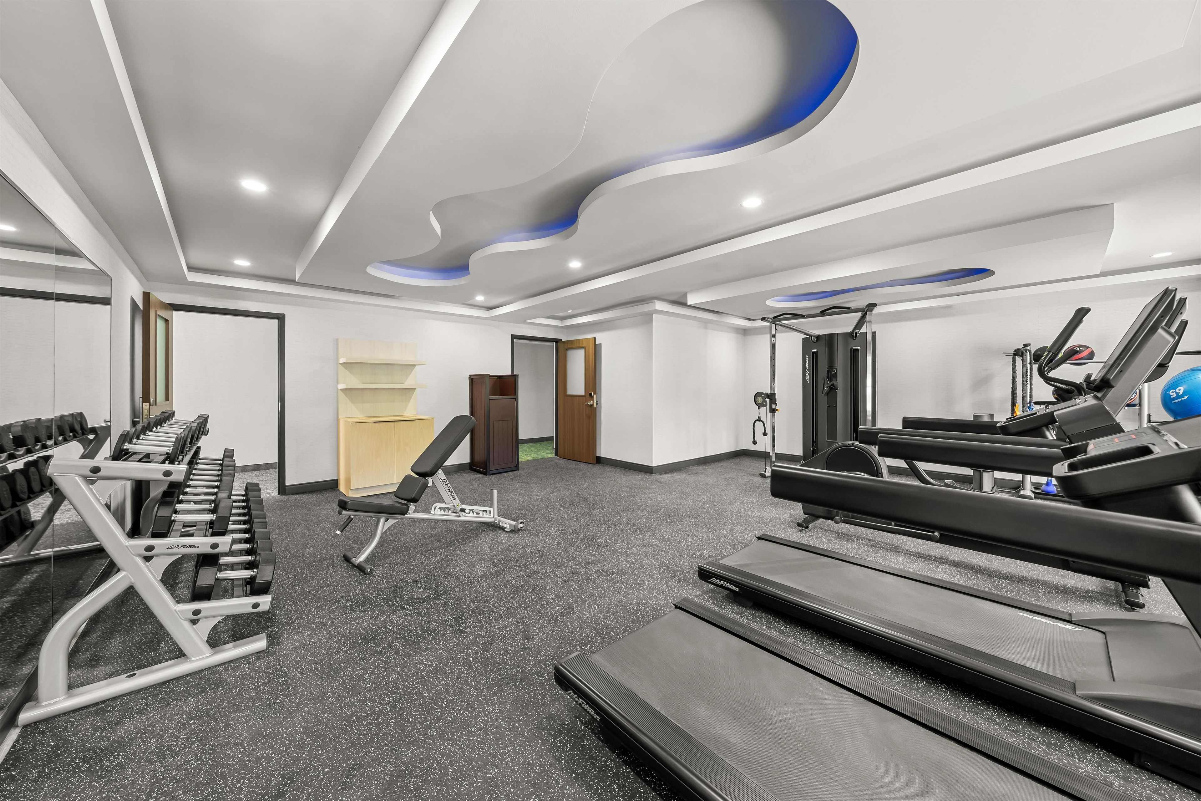 Un gimnasio con cintas de correr, máquinas de pesas y un banco.