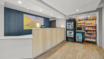 A hotel reception area with a counter, a reception desk, a refrigerator, and a snack vending machine.