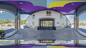 A modern building with a curved facade, large windows, and a parking lot. - Spark by Hilton Milford Boston (Milford)