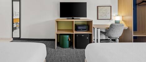 Habitación de hotel con dos camas, un escritorio con silla, televisor, microondas, cubo de basura y armario.