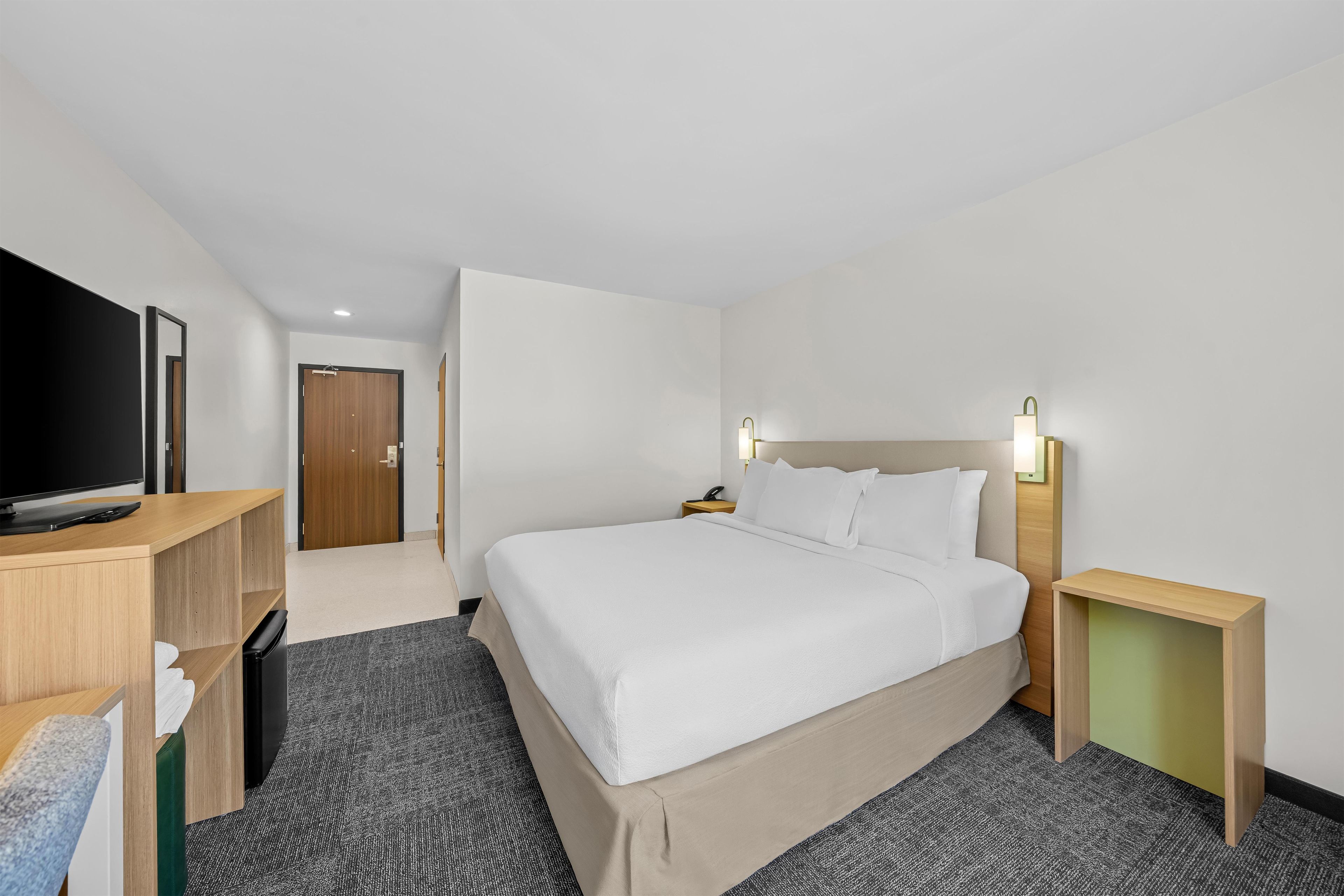 Una habitación de hotel con cama, mesitas de noche, televisor y escritorio.