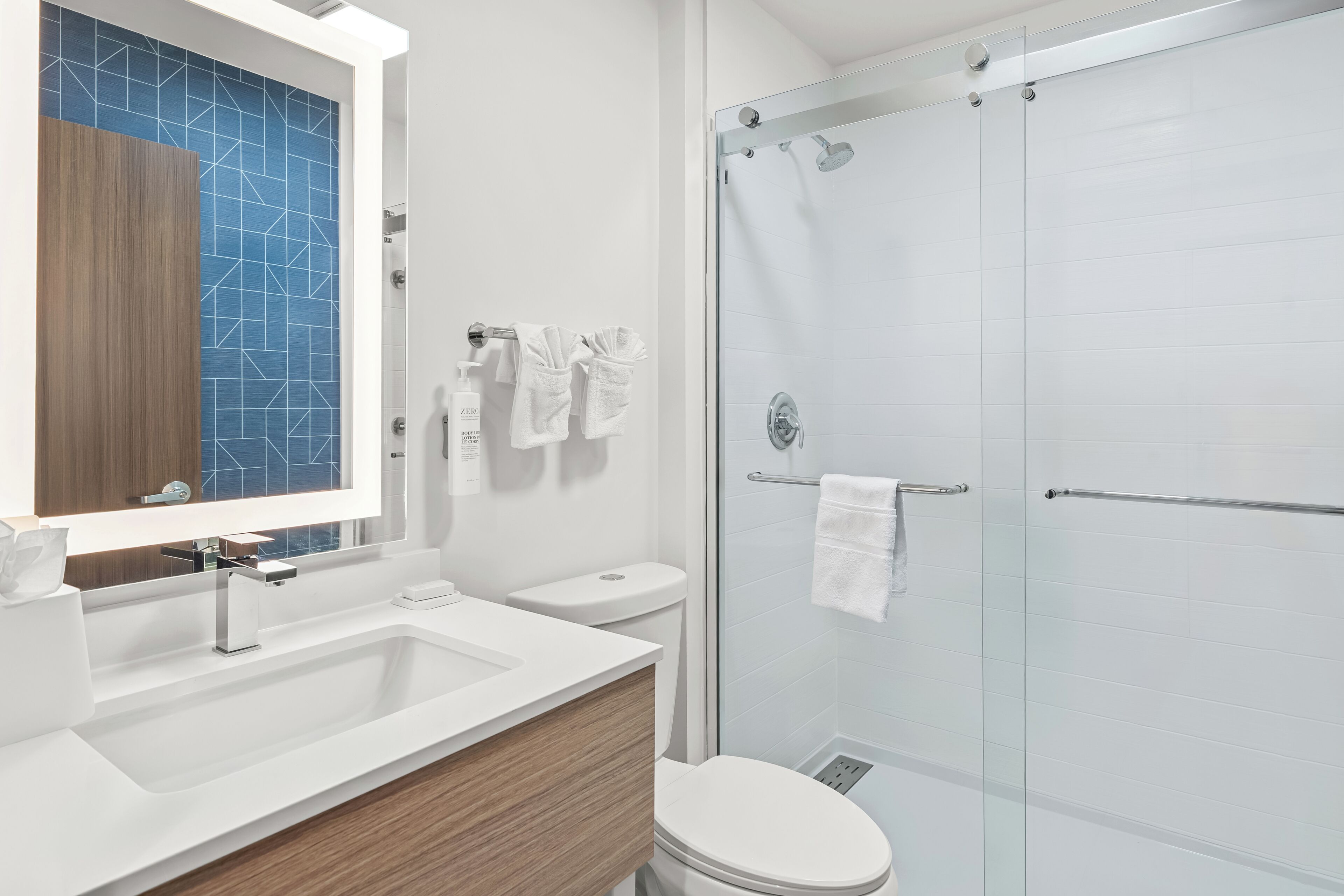 Une salle de bain moderne avec un grand miroir, un lavabo, des toilettes et une douche à parois de verre.