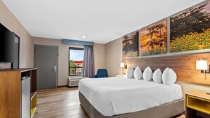 Ein Hotelzimmer mit einem großen Bett, einem Schreibtisch, einem Fernseher und Bildern an der Wand.