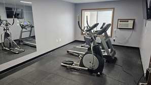 A gym with treadmills, elliptical machines, and a mirrored wall.