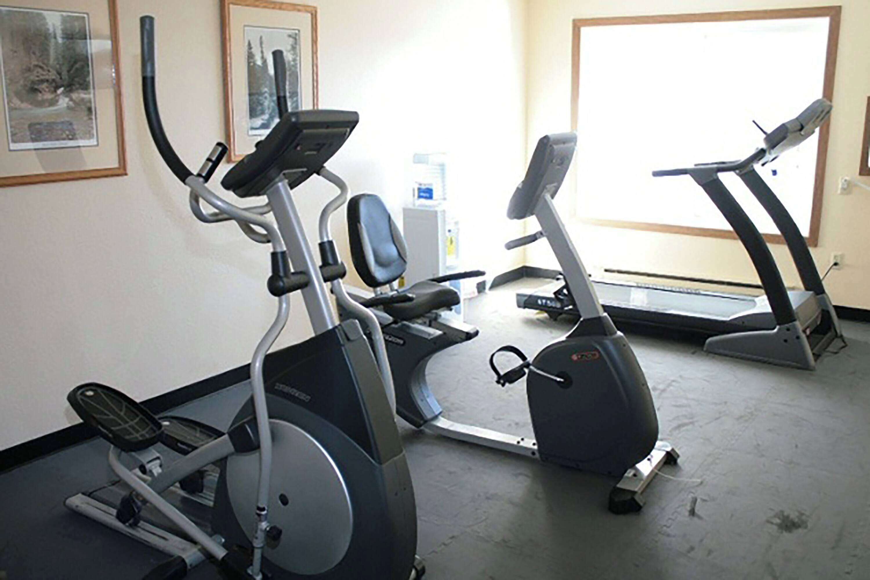 Un gimnasio con bicicletas estáticas, cintas de correr y una máquina elíptica.