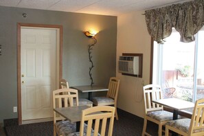 A room with a door, a wall-mounted air conditioner, and two tables with chairs.