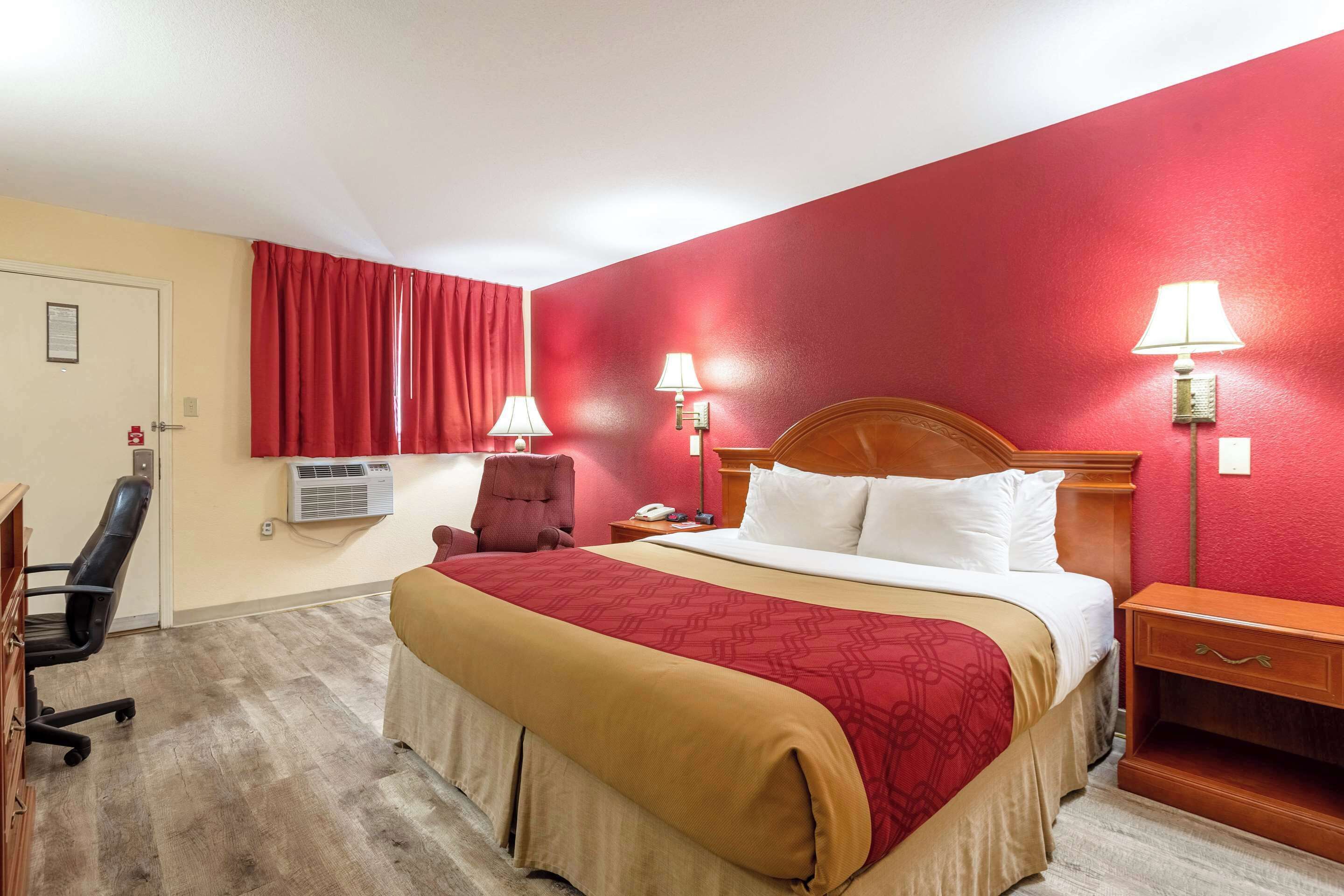 Ein Hotelzimmer mit einem großen Bett, einem Schreibtisch, einem Stuhl und zwei Nachttischlampen.