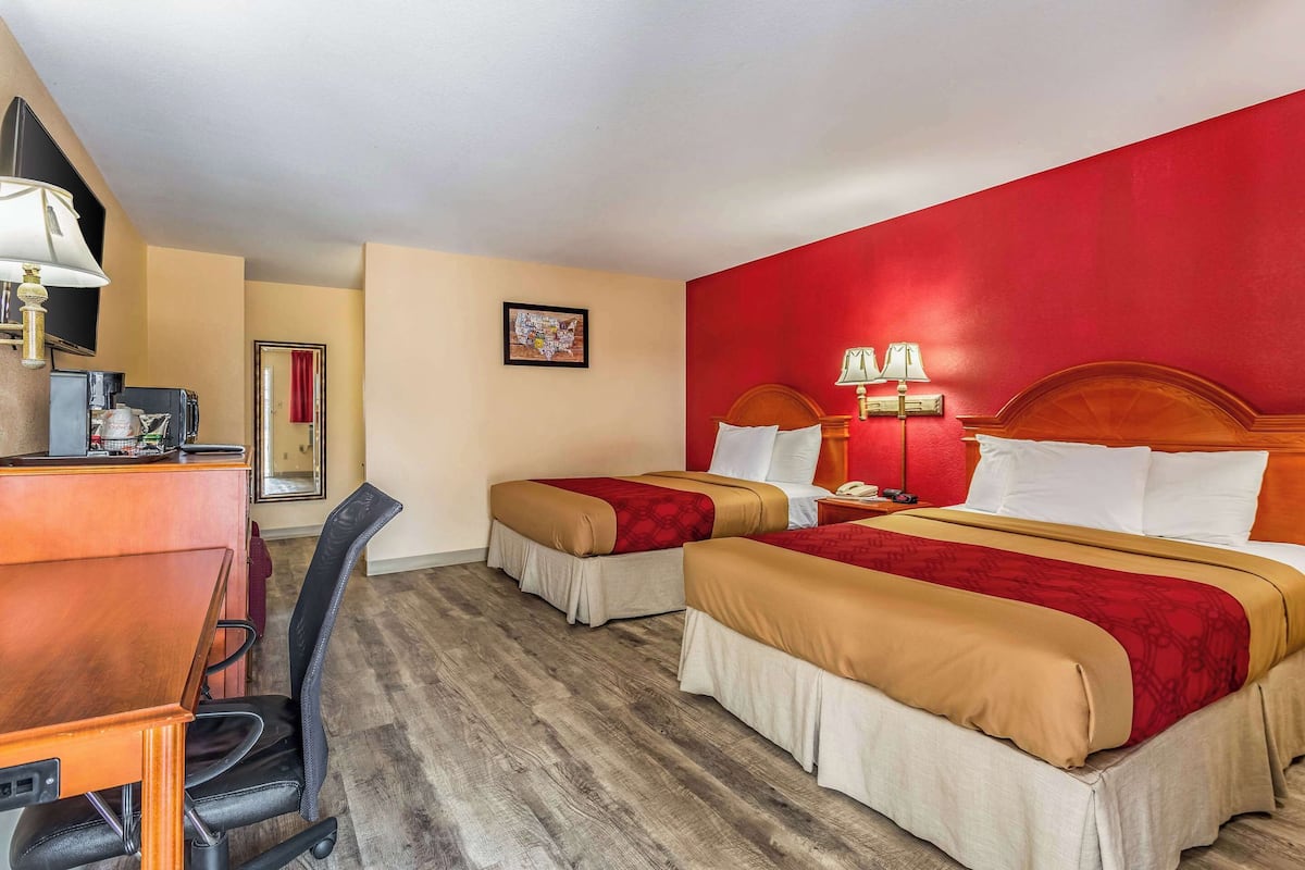 A hotel room with two beds, a desk, and a chair.