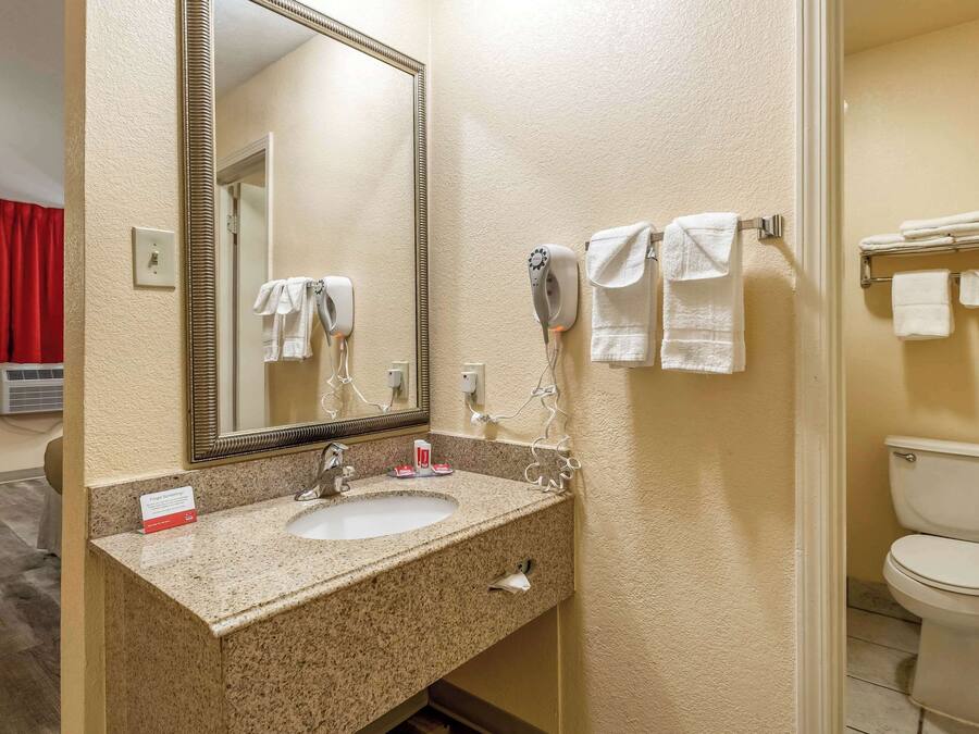 A bathroom with a granite sink, a large mirror, a hairdryer, and a toilet.