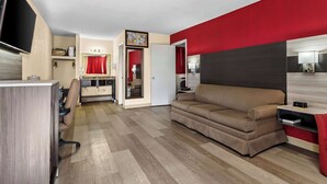 A modern hotel room with a sofa, a desk, a TV, and a red accent wall. - Econo Lodge Inn & Suites Santa Rosa (Santa Rosa)
