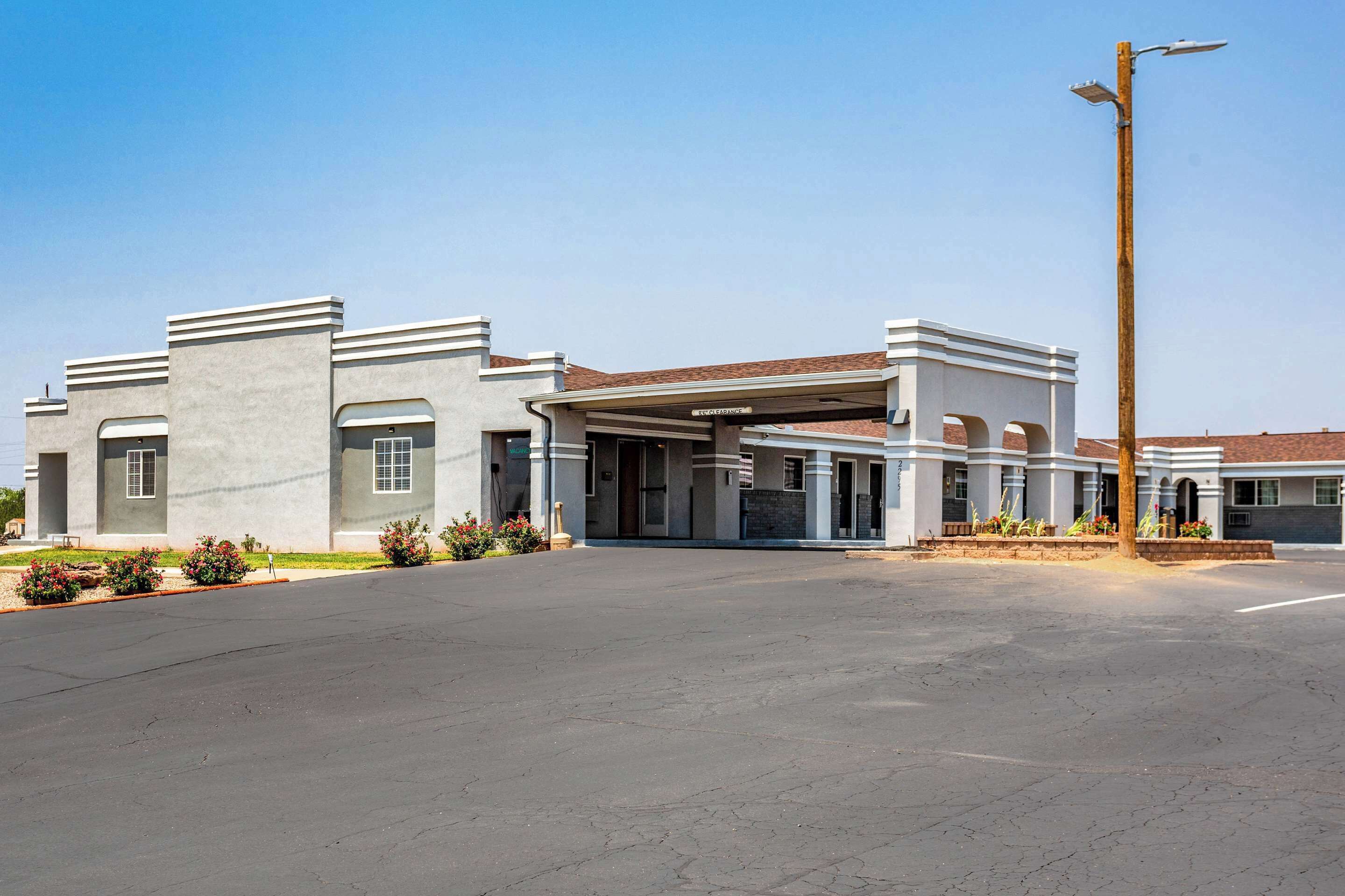 A modern building with a covered entrance, a parking lot, and a clear sky.