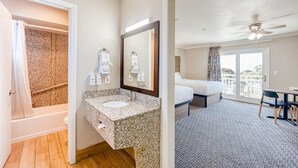 A hotel room with a bathroom, a bed, a balcony, and a dining area. - Harbor House Inn Morro Bay (Morro Bay)