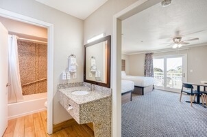 Una habitación de hotel con baño, cama, balcón y zona de comedor.