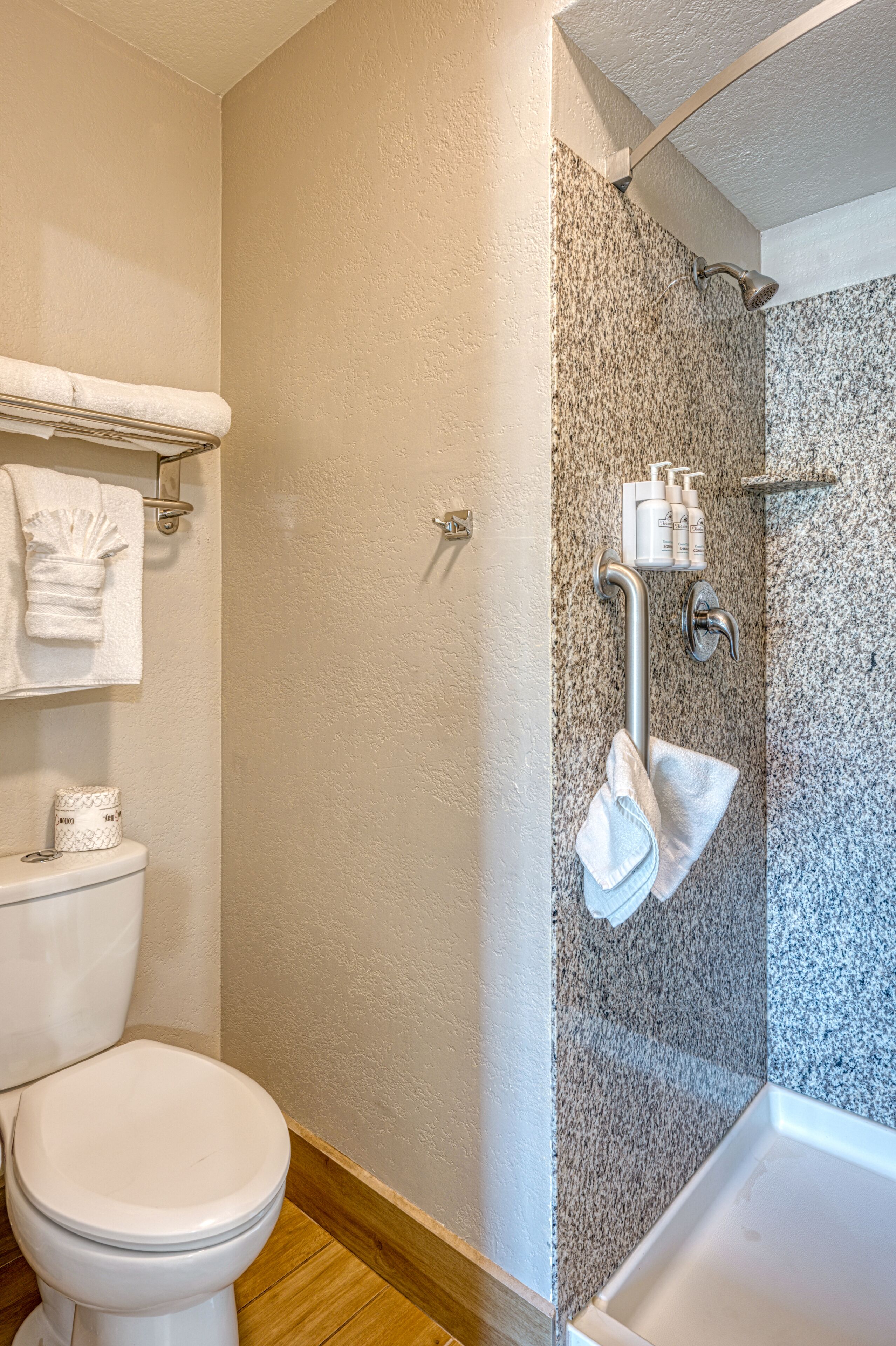 Un baño con inodoro, ducha con puerta de vidrio y toallero con toallas.
