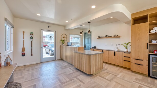 A modern kitchen with wooden cabinets, a central island, and a view of the street. - Harbor House Inn Morro Bay (Morro Bay)