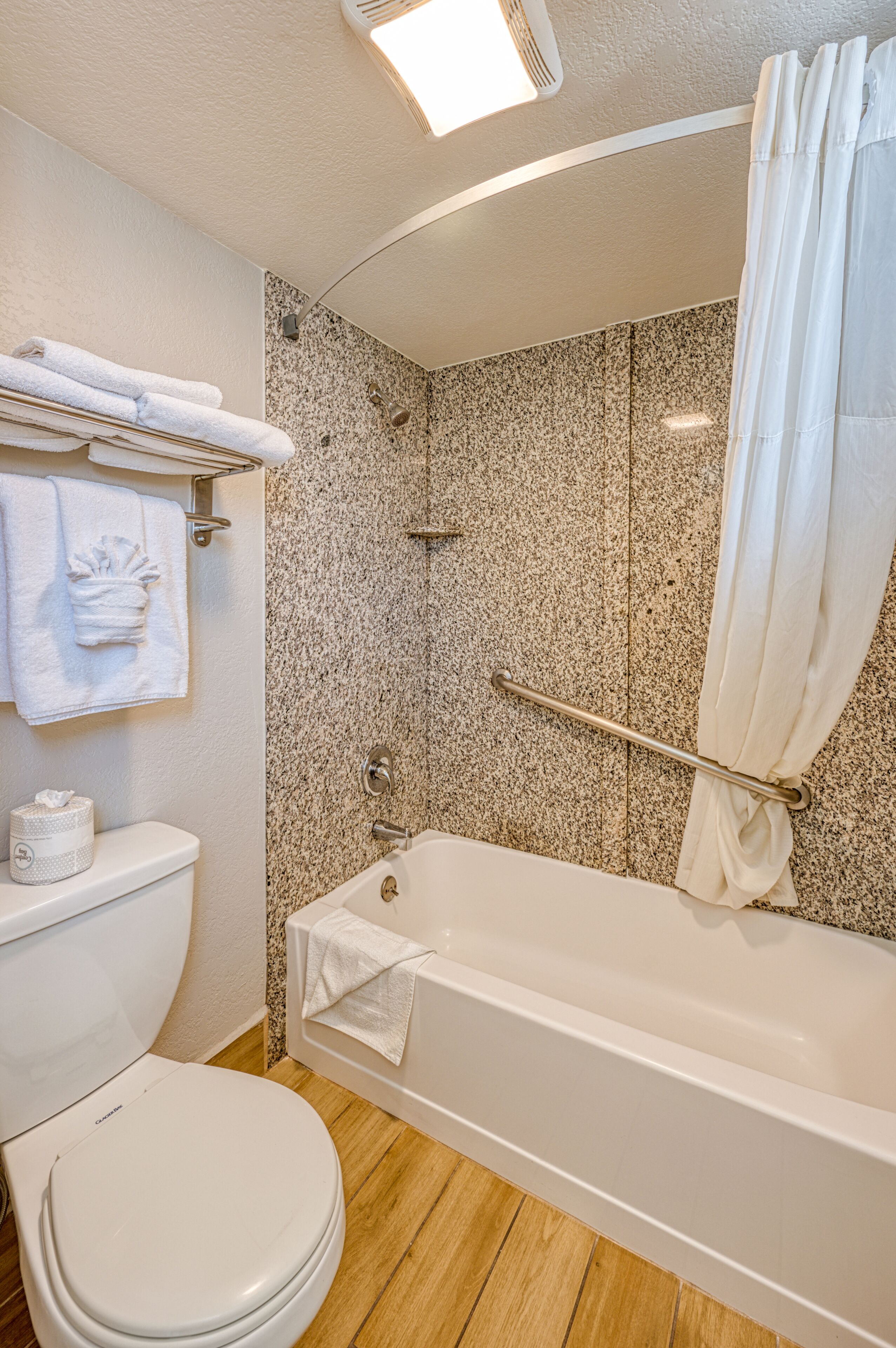 Et badeværelse med toilet, badekar og bruser.
