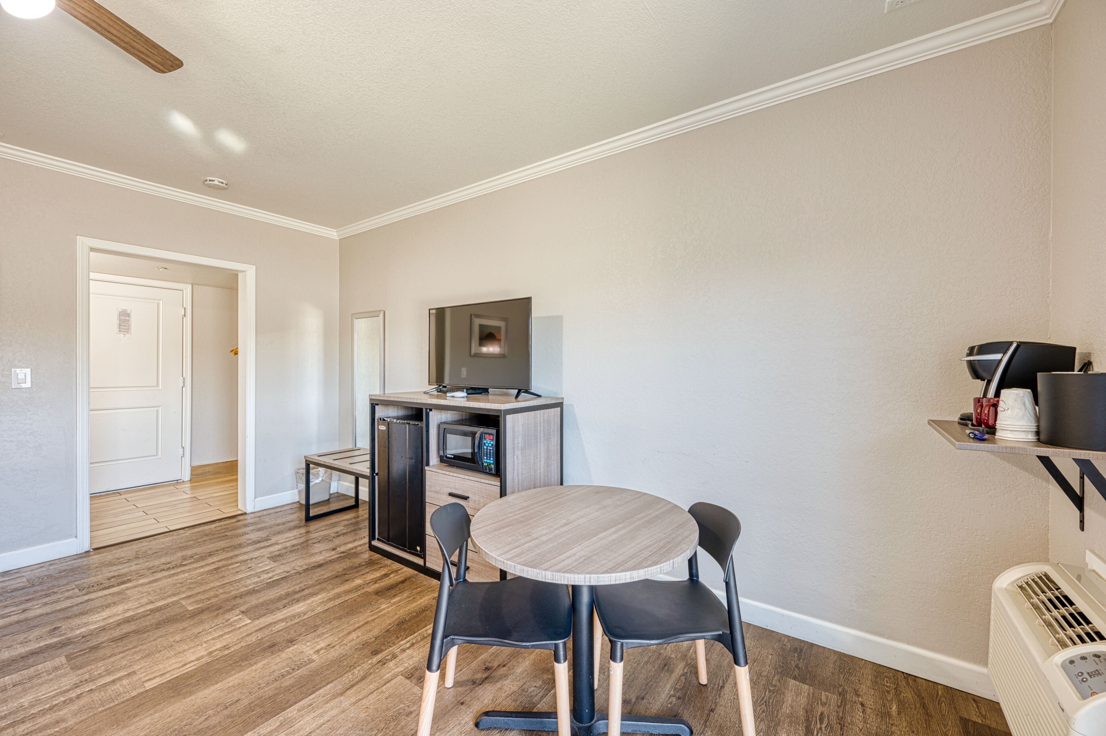 A compact living space with a dining area, kitchenette, and a door leading to another room.