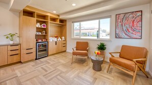 A modern living room with wooden furniture, a built-in kitchen, and a large window offering a view of the outside. - Harbor House Inn Morro Bay (Morro Bay)