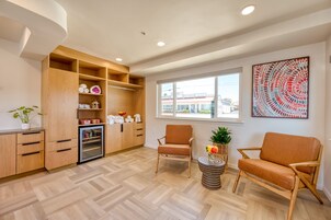 Una sala de estar moderna con muebles de madera, cocina integrada y un gran ventanal con vistas al exterior.