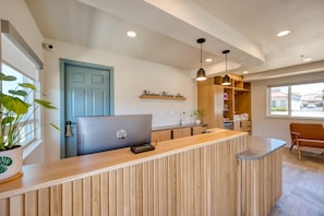 Un comptoir d’accueil avec un ordinateur portable, une porte bleue et une enseigne indiquant « Nahar House Inn ».