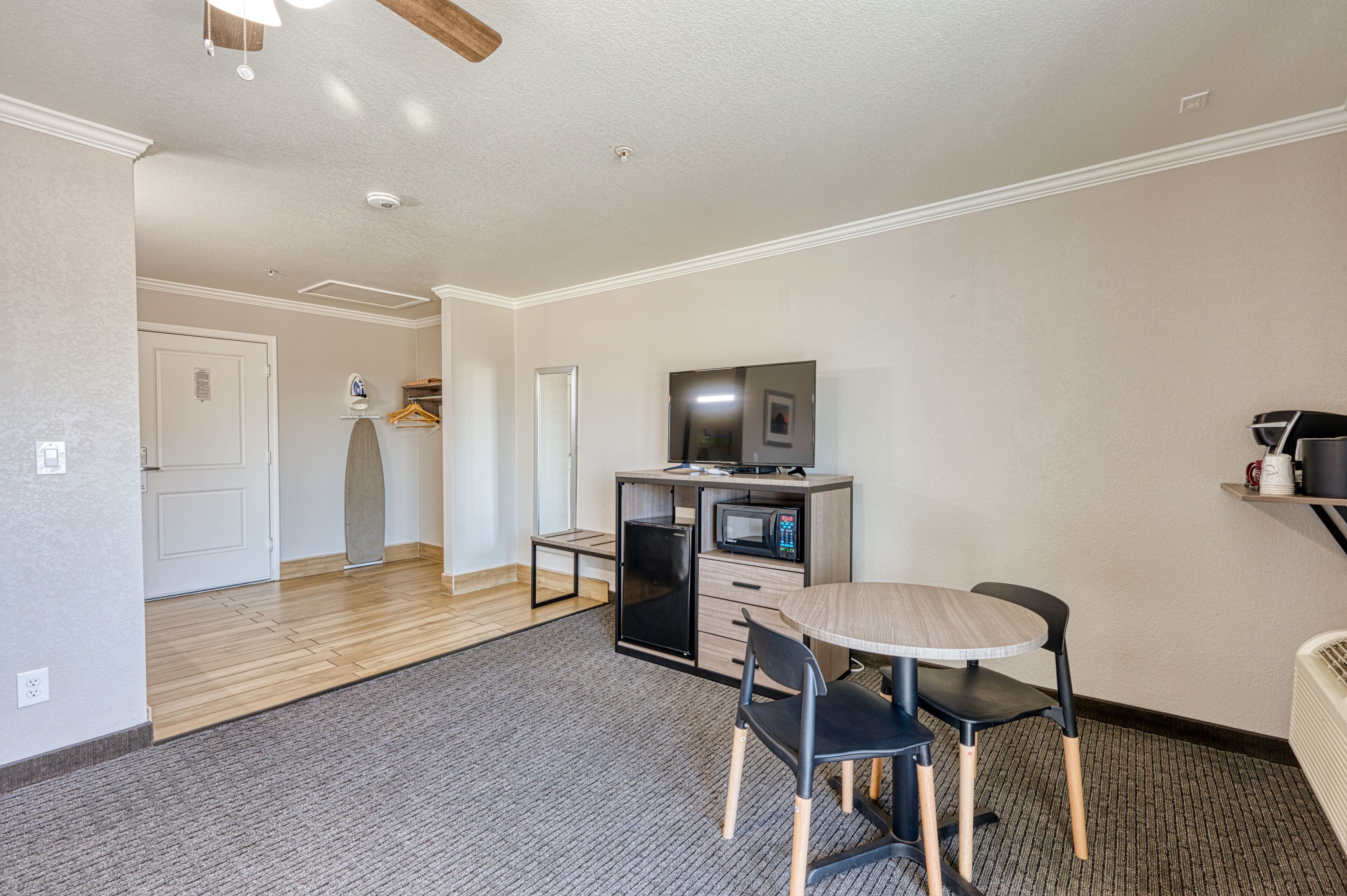 A compact room with a kitchenette, a dining area with a table and chairs, and a television on a cabinet.