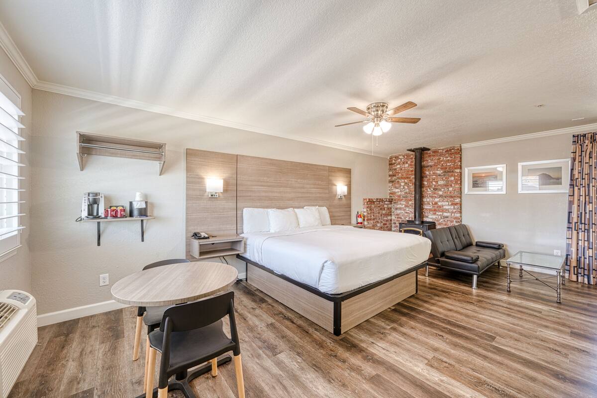 A modern hotel room with a large bed, a desk, a chair, and a ceiling fan.