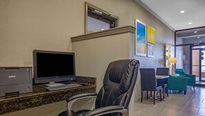 Un espace d’accueil d’hôtel comprenant un ordinateur, une imprimante et un fauteuil en cuir.