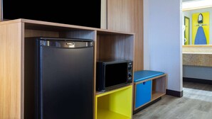 Une cuisine compacte avec un réfrigérateur noir, un four à micro-ondes et un meuble de rangement jaune.