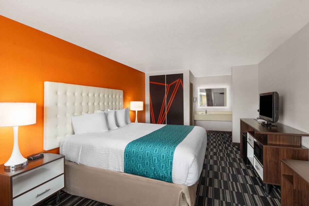 A hotel room with a large bed, a TV, a desk, and a wardrobe.