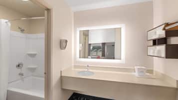A bathroom with a bathtub, a sink, a mirror, and a shelf with toiletries.